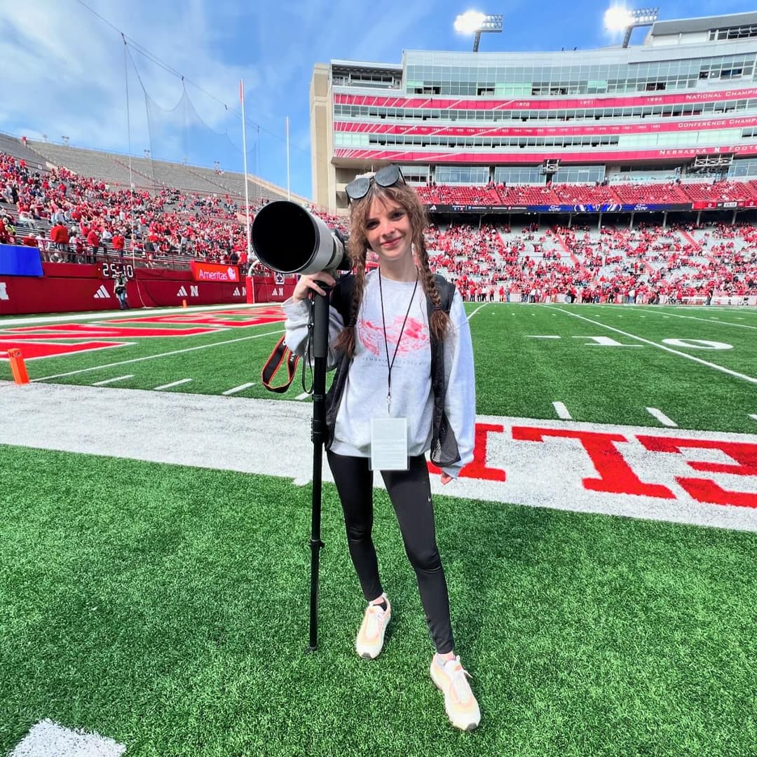Husker poses with a camera on the field at Memorial Stadium.