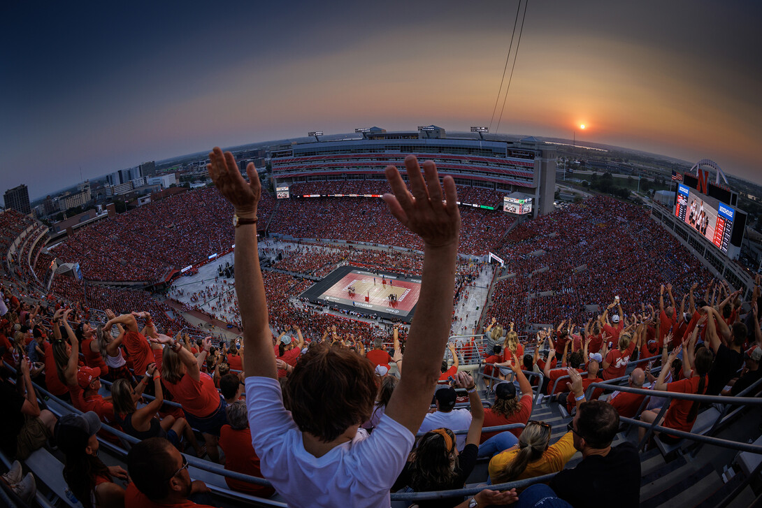 Fans raising arms while looking down at Volleyball court in Memorial Stadium