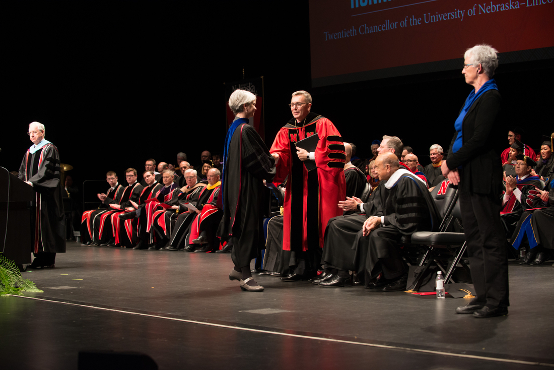 Chancellor Ronnie Green shakes hands with Professor Joy Castro on stage at the installation ceremony