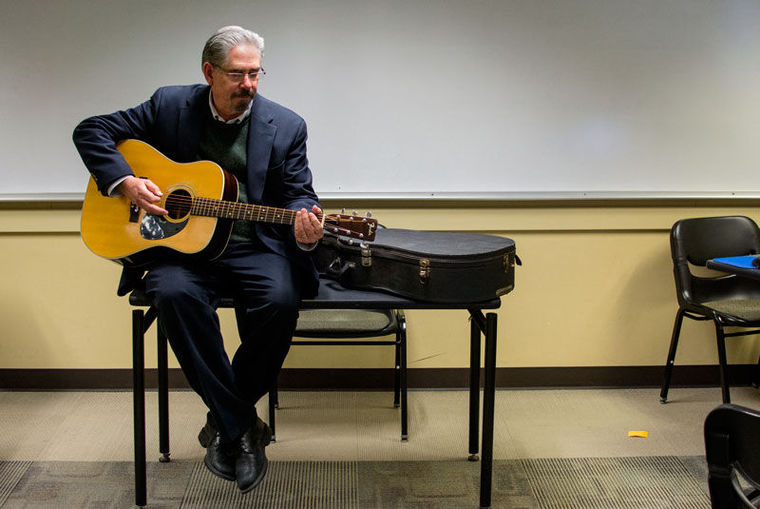 Steve Buhler draws upon his musical talent - playing guitar - to enrich his classes; links to news story