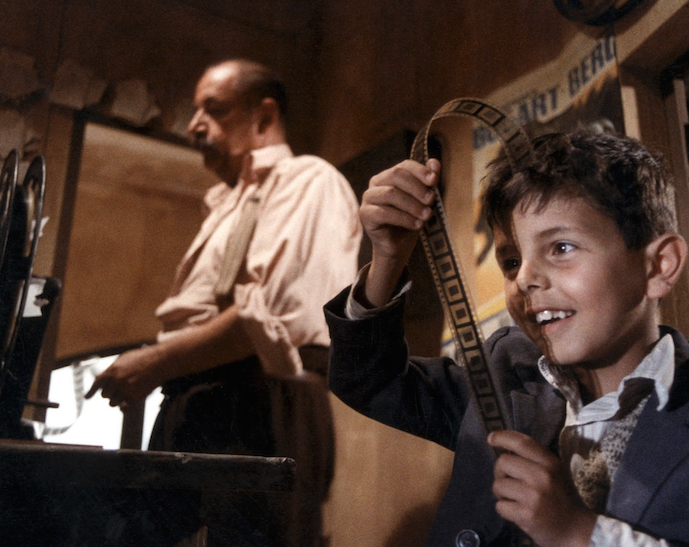 A man and a young boy behind a reel at a movie theater