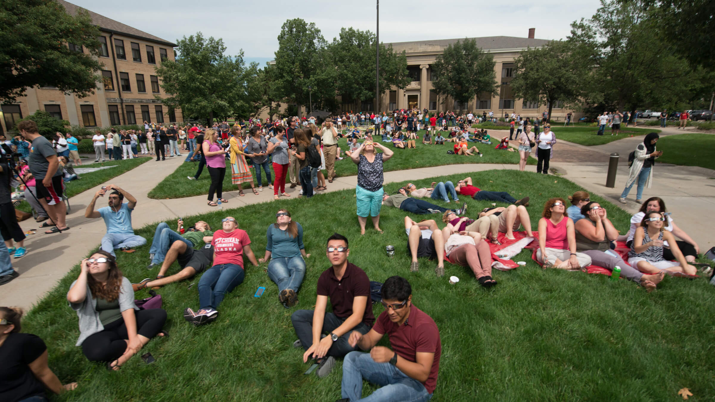People sitting on East Campus green space while viewing eclipse