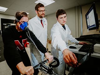 Students conduct an athletic performance study supervised by a professor.