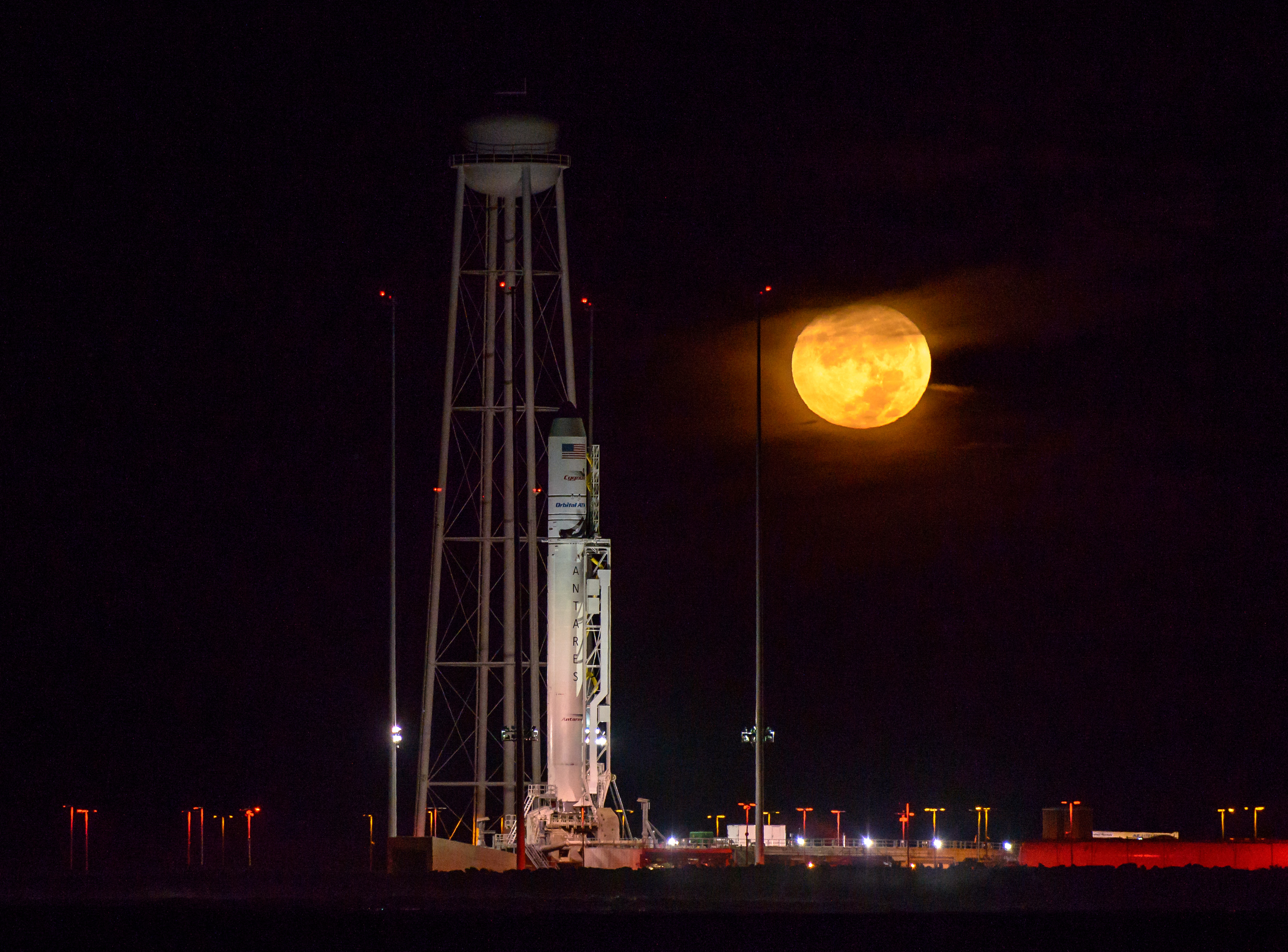 Photo Credit: Antares rocket upright in front of the full moon.