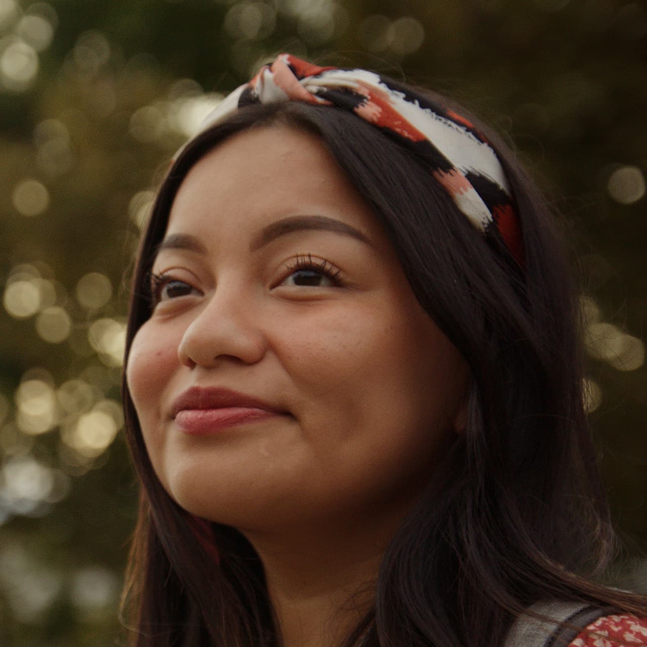 Portrait of Isela Tercero in front of a tree, looking off into the distance