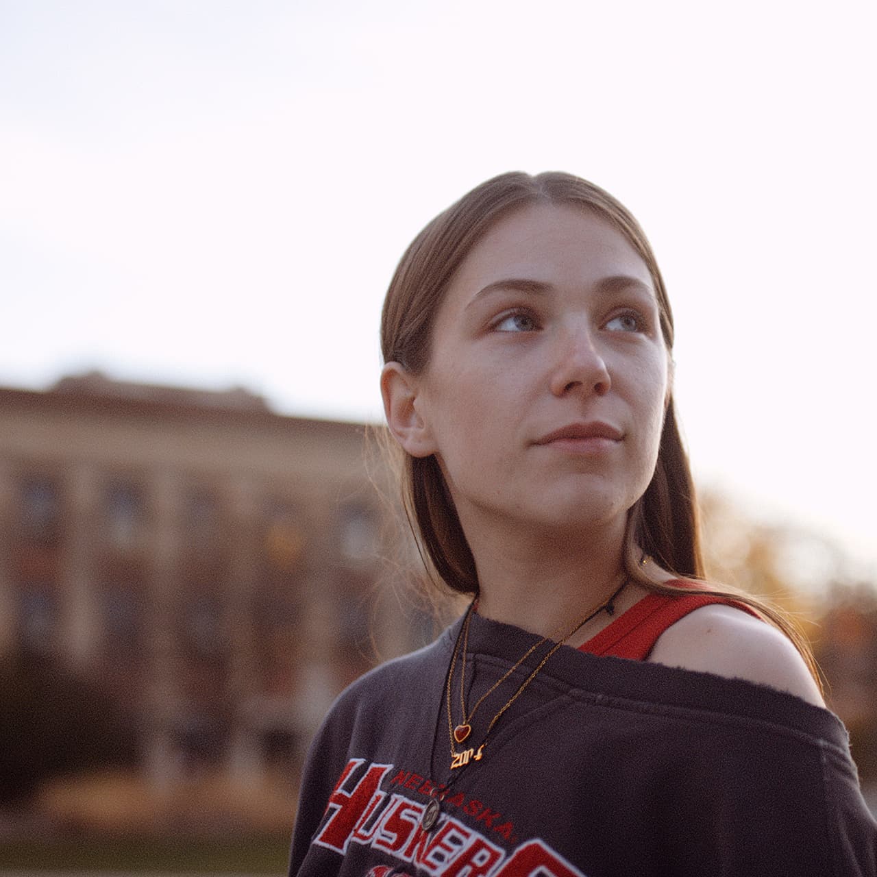 Kyanne Casperson, standing in front of a campus building, looks over her shoulder off into the distance