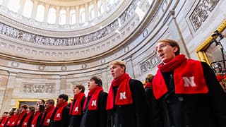 A choir wearing red Nebraska scarves performs in the U.S. Capitol Rotunda.