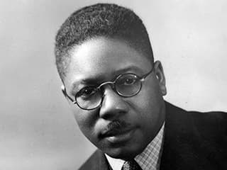 Black-and-white portrait of Aaron Douglas wearing a coat and tie.