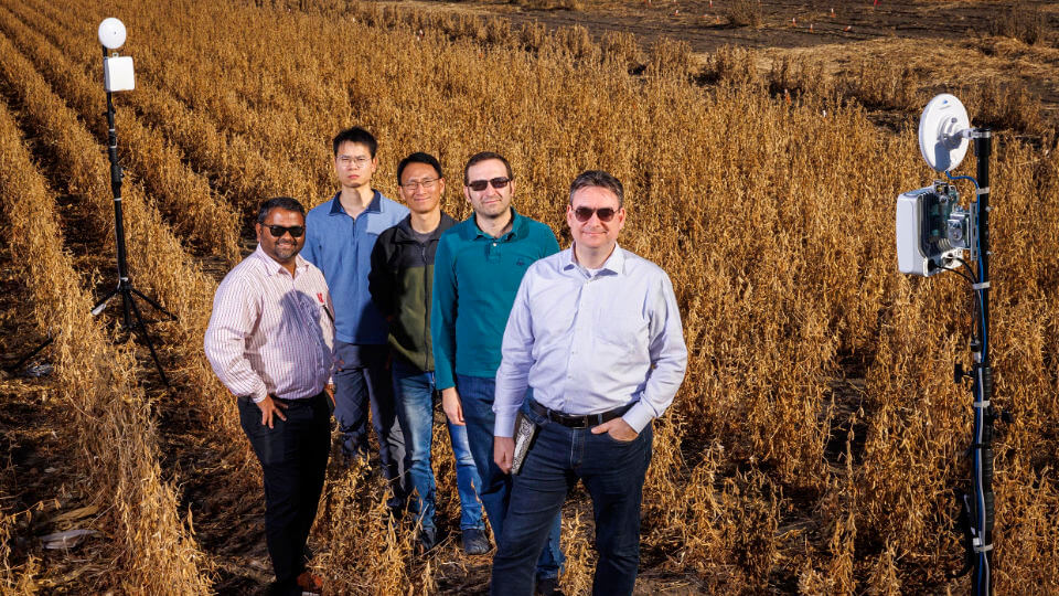 Faculty members standing in field with antenna