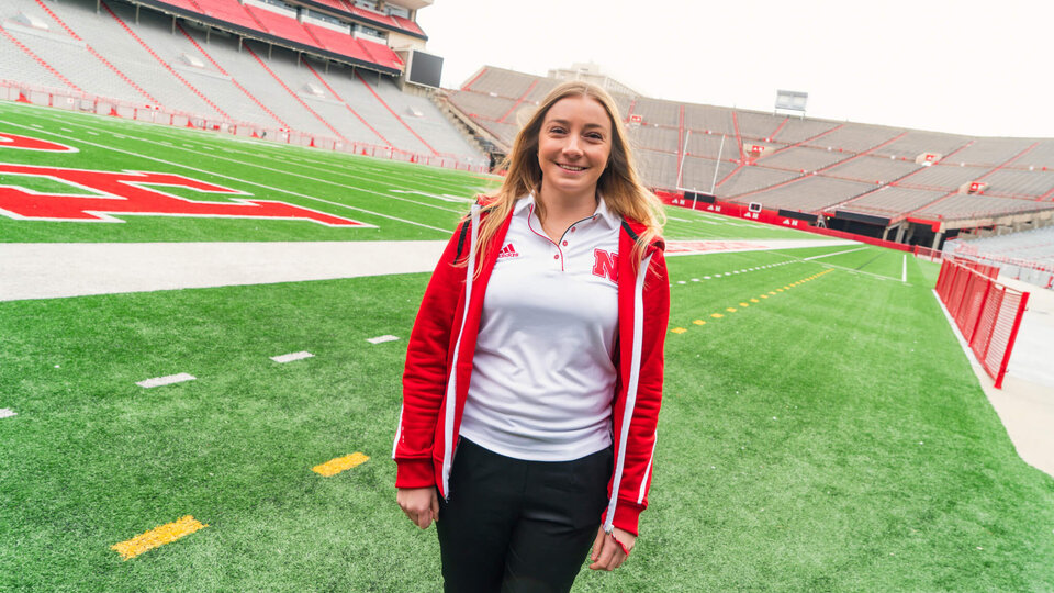 Student standing on sidelines of football field in Memorial Stadium