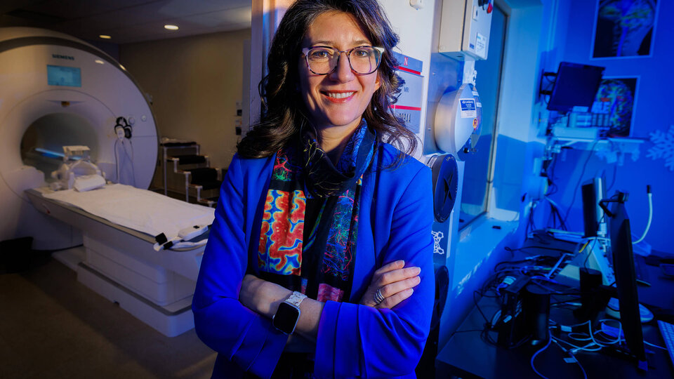 Faculty member standing in front of MRI machine with blue light