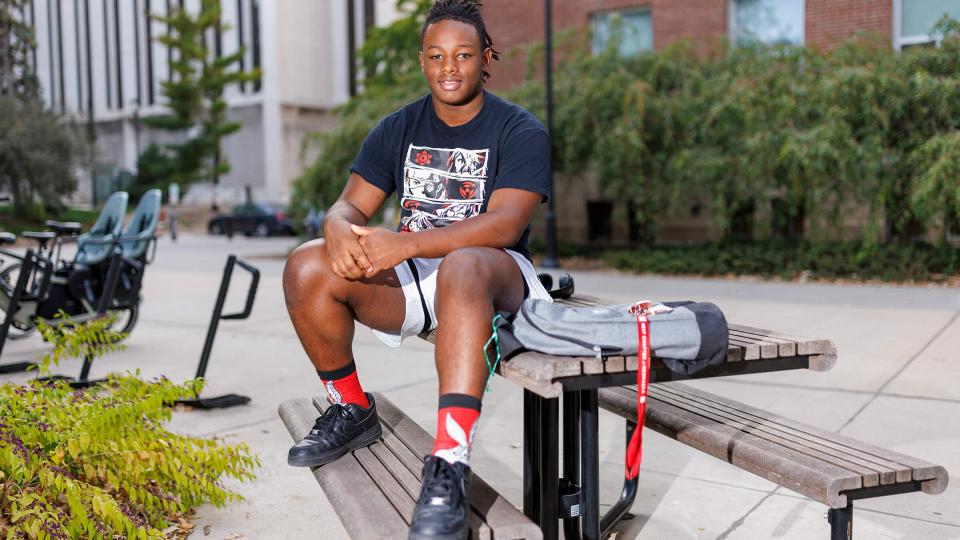 Student sitting on top of picnic table outside building